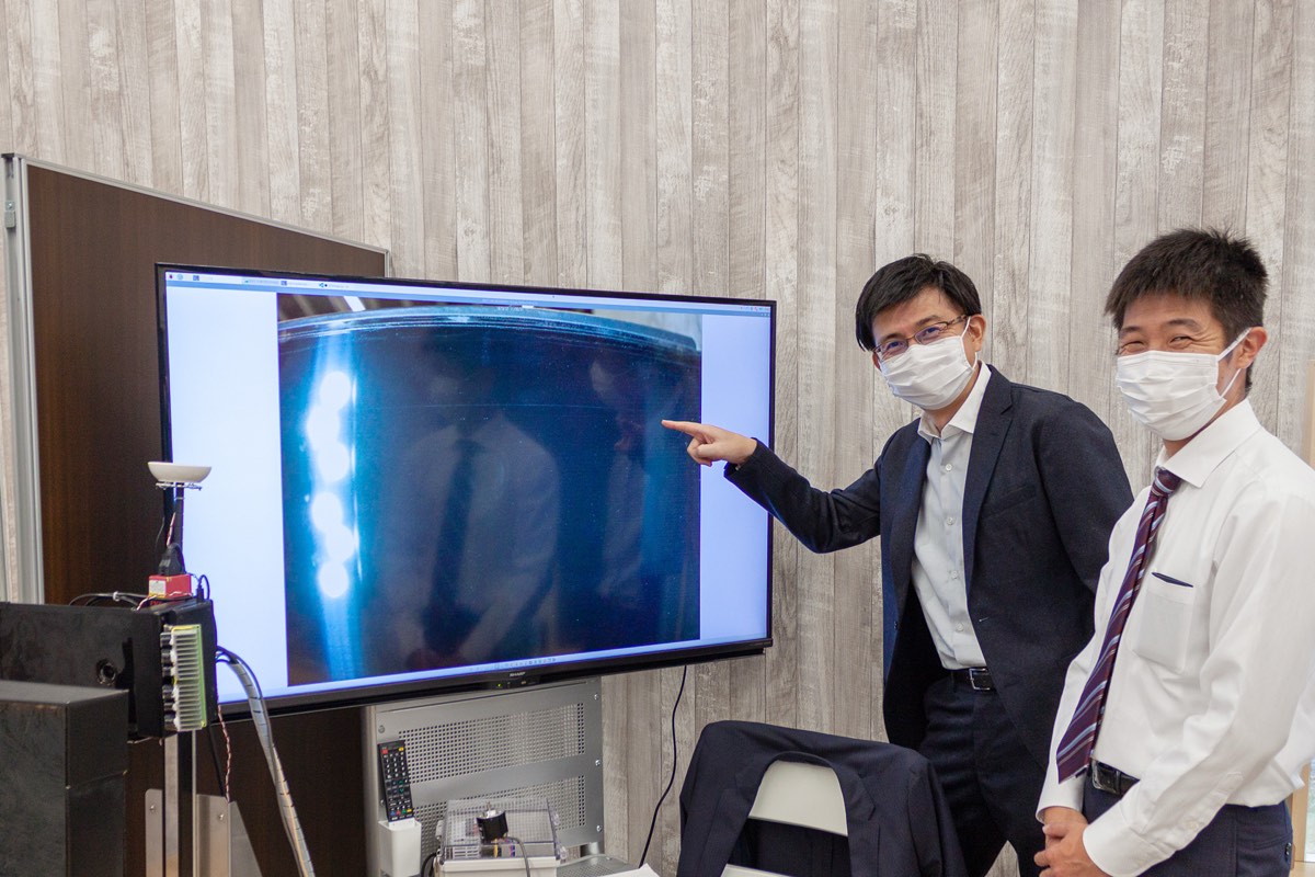 Engineers reviewing an inspection image on a screen beside the line